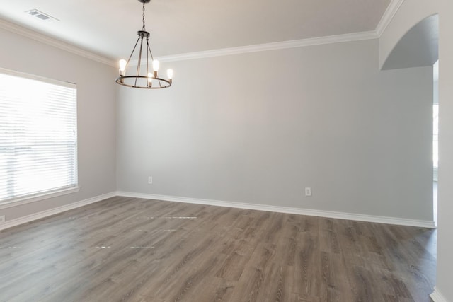 empty room with crown molding, dark hardwood / wood-style floors, and a chandelier