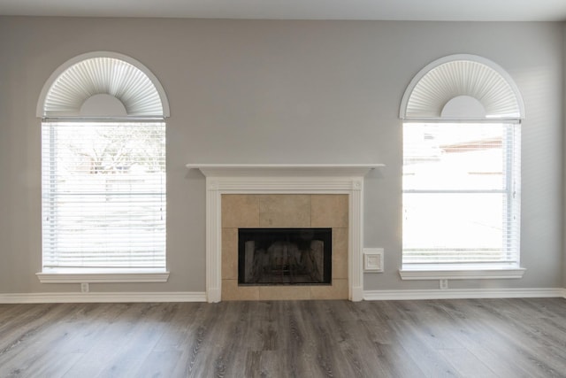 unfurnished living room with dark wood-type flooring, a wealth of natural light, and a fireplace