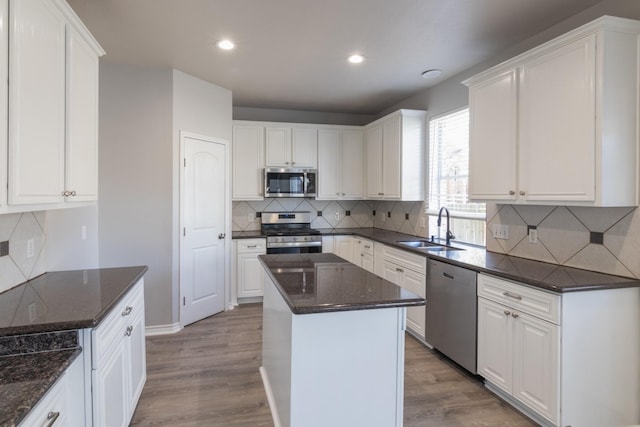 kitchen with sink, white cabinetry, light wood-type flooring, appliances with stainless steel finishes, and a kitchen island