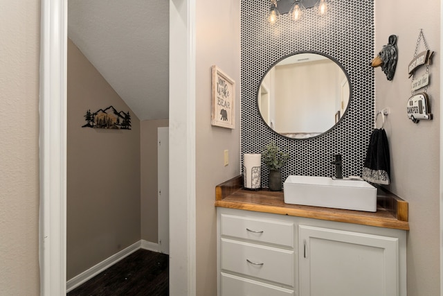 bathroom featuring vanity, lofted ceiling, and tasteful backsplash