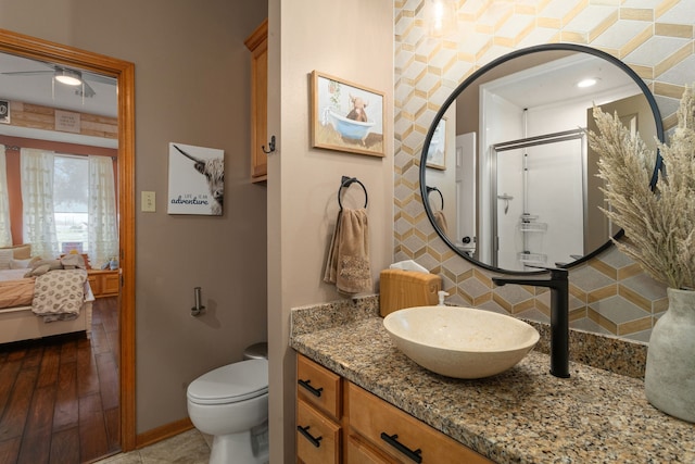 bathroom with decorative backsplash, vanity, wood-type flooring, toilet, and a shower with shower door