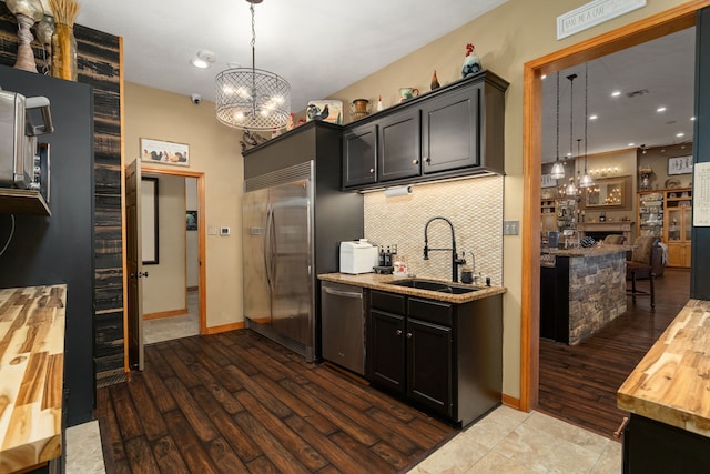 kitchen featuring sink, tasteful backsplash, butcher block countertops, decorative light fixtures, and appliances with stainless steel finishes