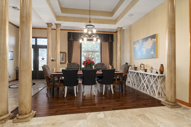 dining space featuring ornate columns, wood-type flooring, a healthy amount of sunlight, and an inviting chandelier