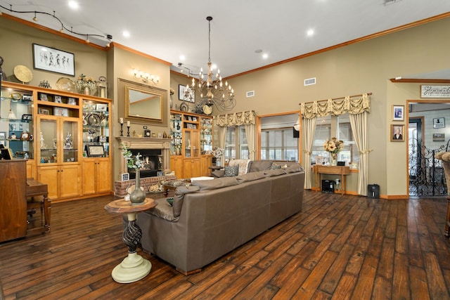 living room featuring a towering ceiling, dark hardwood / wood-style flooring, an inviting chandelier, and ornamental molding