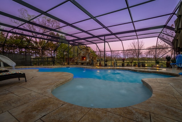 pool at dusk featuring a fireplace, glass enclosure, and a patio area