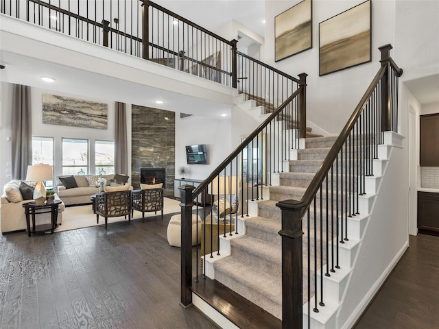 1412 River Point Dr, Friendswood, TX 77546 - stairway featuring a high ceiling, a tiled fireplace, wood finished floors, and baseboards