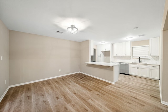 kitchen featuring backsplash, sink, stainless steel dishwasher, light wood-type flooring, and white cabinetry