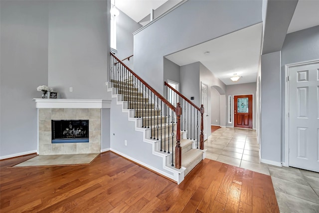 foyer with a towering ceiling, wood-type flooring, and a tiled fireplace