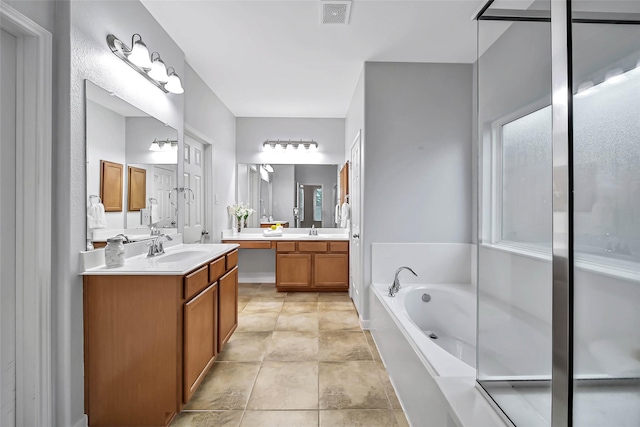 full bath featuring a bath, two vanities, a sink, and visible vents