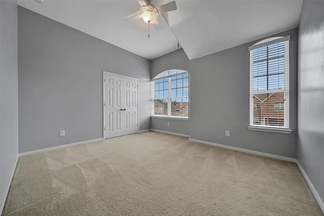 unfurnished room with light carpet, ceiling fan, lofted ceiling, and baseboards