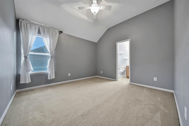 spare room featuring light carpet, ceiling fan, vaulted ceiling, and baseboards