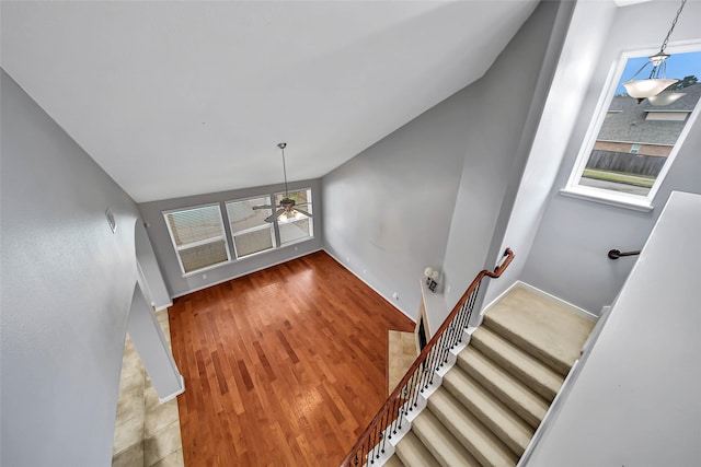 staircase featuring lofted ceiling, baseboards, and wood finished floors