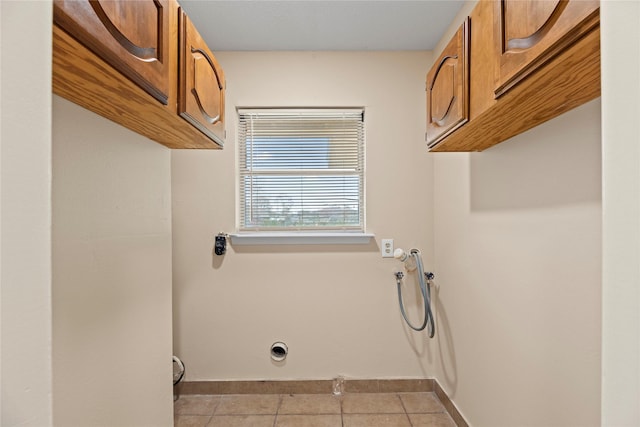 laundry area with light tile patterned flooring and cabinets