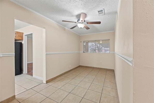 empty room with a textured ceiling, ceiling fan, light tile patterned flooring, and crown molding