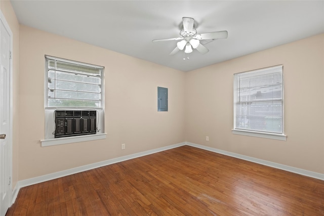 unfurnished room featuring electric panel, plenty of natural light, and hardwood / wood-style flooring