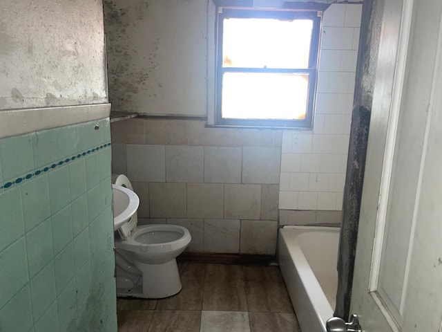 bathroom with a bathtub, toilet, and tile walls