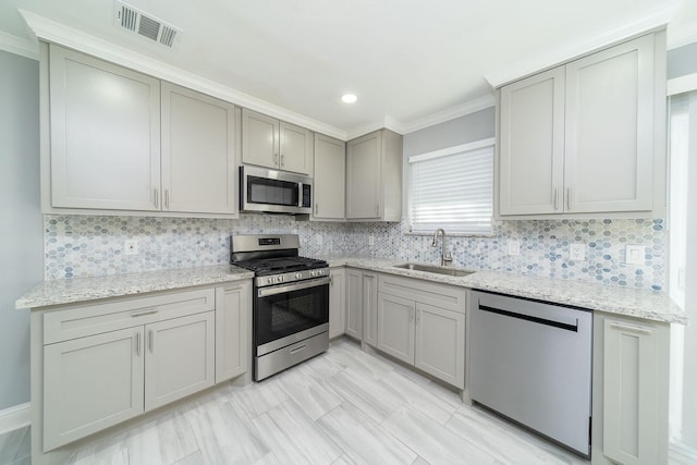 kitchen featuring backsplash, light stone countertops, sink, and stainless steel appliances