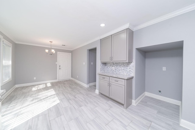 kitchen featuring tasteful backsplash, light stone counters, decorative light fixtures, a notable chandelier, and gray cabinets