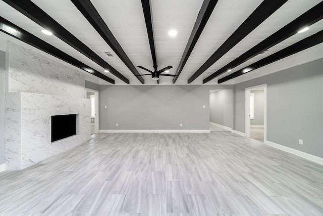 unfurnished living room featuring a fireplace, light wood-type flooring, ceiling fan, and beamed ceiling