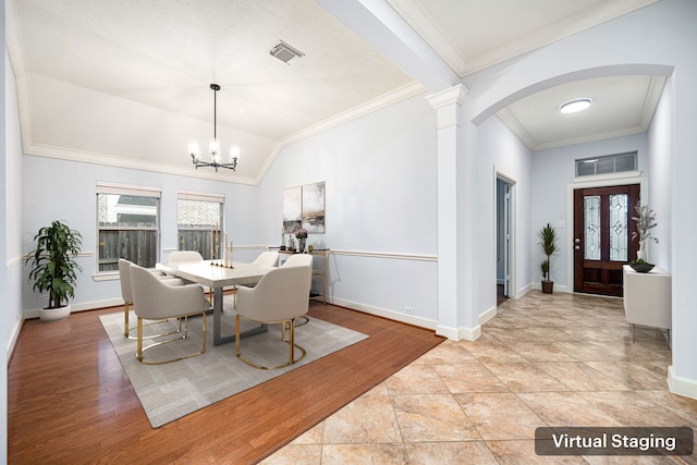 dining area with a chandelier, lofted ceiling, light wood-type flooring, and ornamental molding