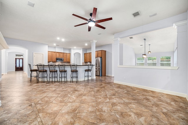 kitchen with ceiling fan, stainless steel appliances, pendant lighting, decorative backsplash, and a breakfast bar