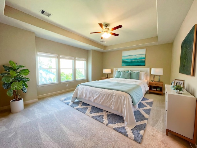 bedroom featuring light colored carpet, ceiling fan, and a tray ceiling