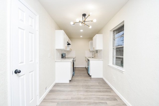 kitchen featuring backsplash, sink, white cabinetry, stainless steel appliances, and a chandelier