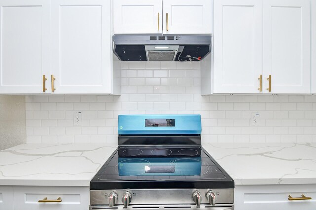 kitchen featuring ventilation hood, light stone counters, stainless steel range oven, and white cabinets