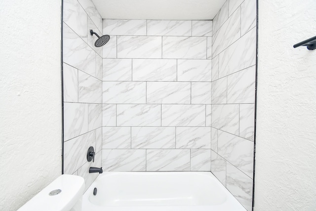 bathroom featuring toilet and tiled shower / bath