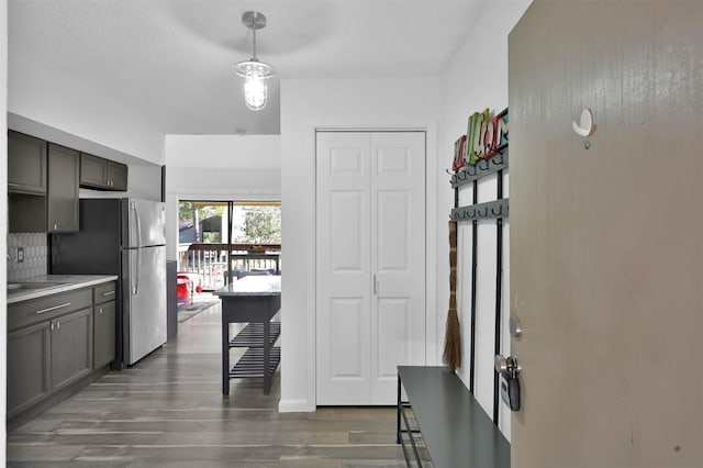 kitchen featuring stainless steel fridge, decorative backsplash, and dark wood-type flooring