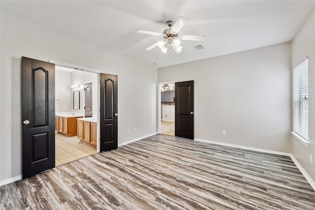 unfurnished bedroom featuring ensuite bath, ceiling fan, and light wood-type flooring