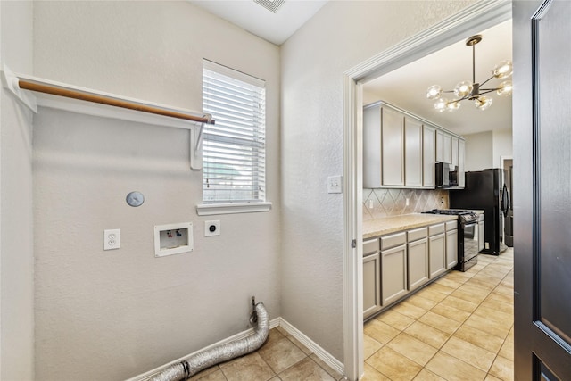 clothes washing area with hookup for a washing machine, light tile patterned flooring, a chandelier, and hookup for an electric dryer