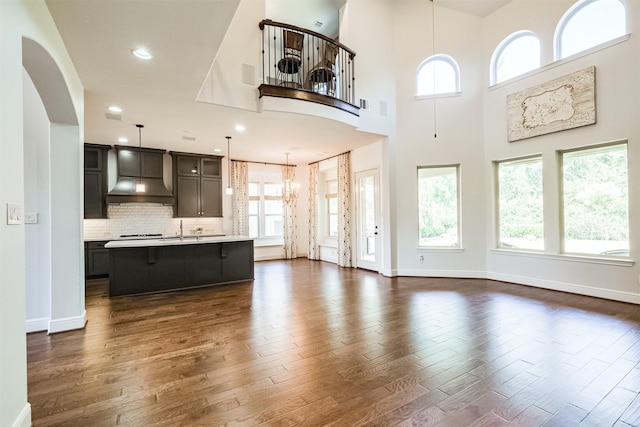 unfurnished living room with dark hardwood / wood-style floors, sink, a high ceiling, and a chandelier