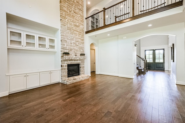 unfurnished living room with dark hardwood / wood-style floors, a fireplace, and a high ceiling