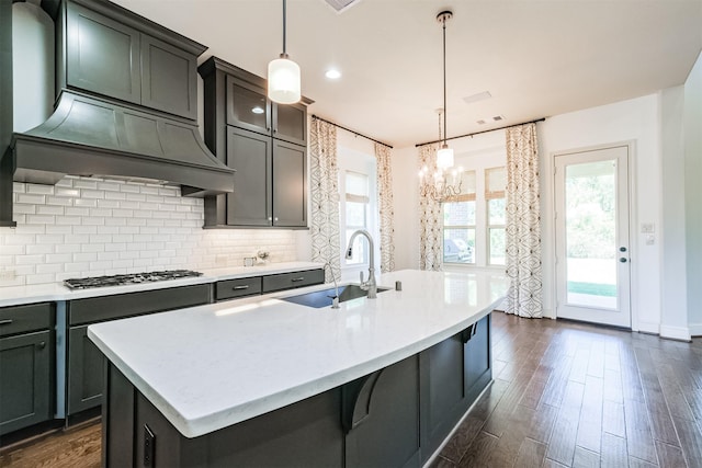 kitchen with hanging light fixtures, sink, a kitchen island with sink, and stainless steel gas stovetop