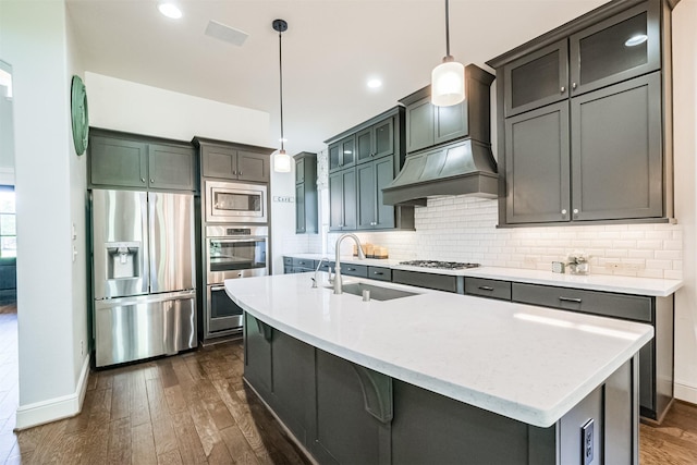 kitchen featuring pendant lighting, sink, dark hardwood / wood-style floors, an island with sink, and appliances with stainless steel finishes