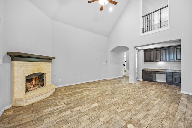 unfurnished living room featuring high vaulted ceiling, ceiling fan, and a fireplace