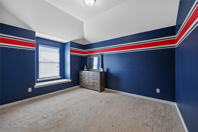 unfurnished bedroom with vaulted ceiling and carpet floors