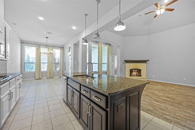 kitchen featuring dark brown cabinets, white cabinets, dark stone counters, and sink