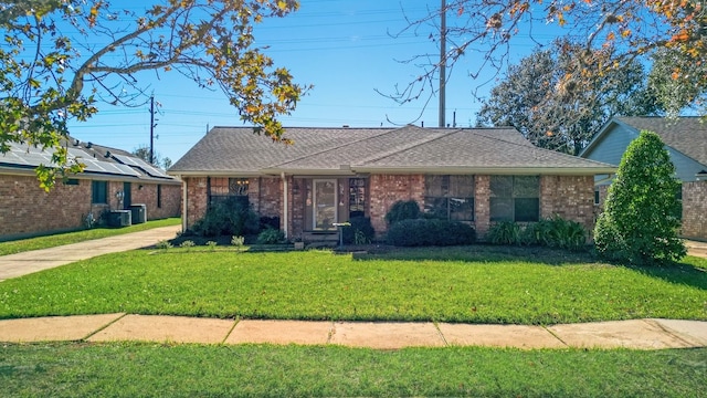 ranch-style home with solar panels, central air condition unit, and a front yard