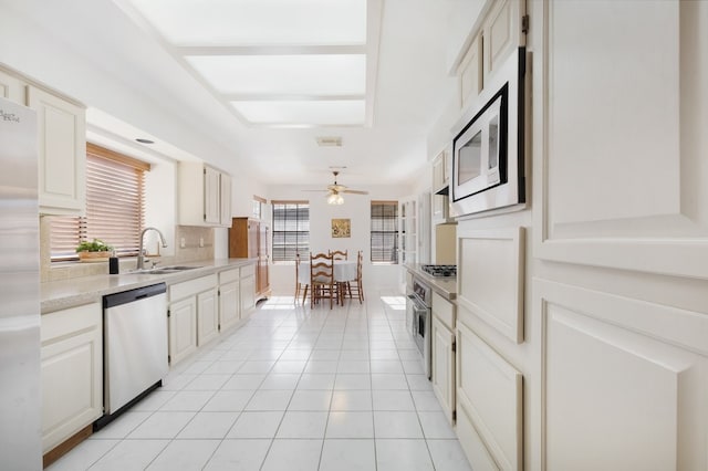 kitchen with white cabinets, sink, ceiling fan, appliances with stainless steel finishes, and light tile patterned flooring