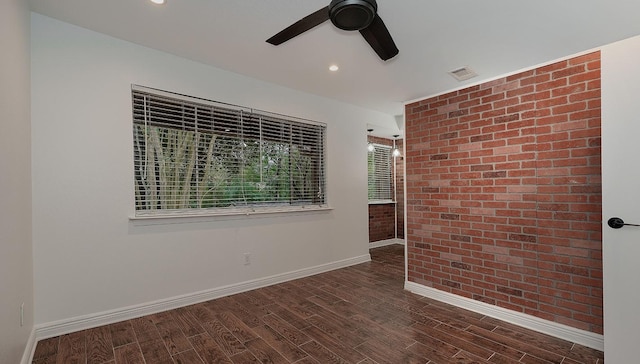 unfurnished room with brick wall, ceiling fan, and dark hardwood / wood-style floors