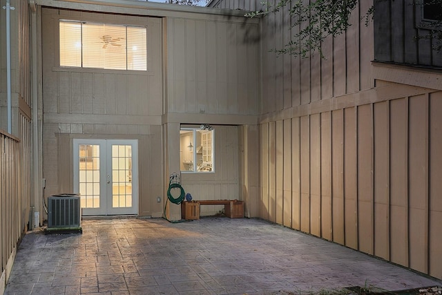 unfurnished living room with french doors, wood walls, and plenty of natural light