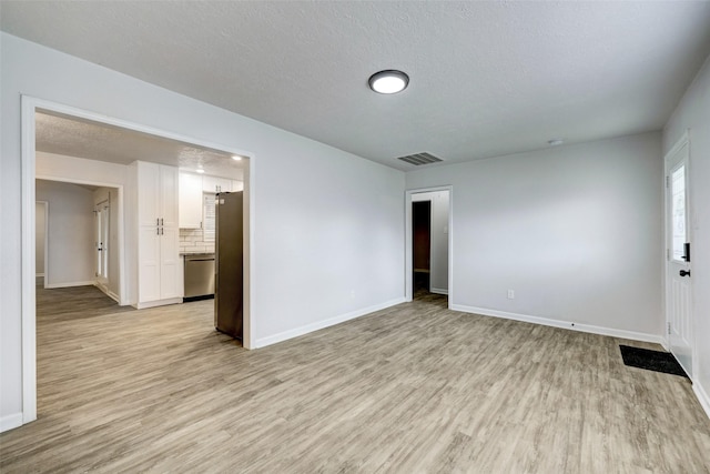 spare room with a textured ceiling and light hardwood / wood-style floors