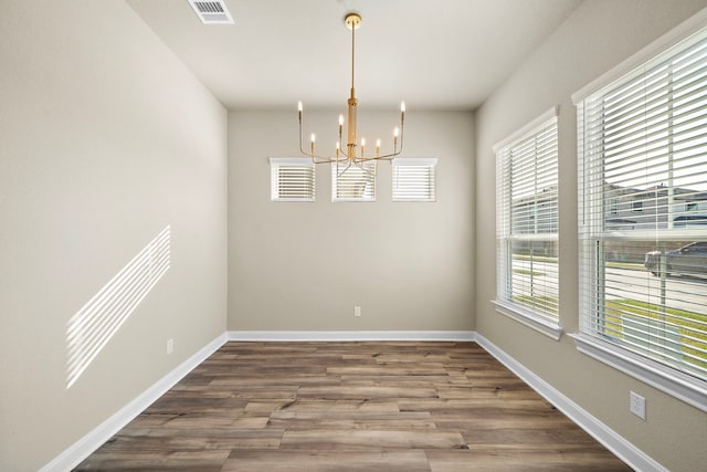 unfurnished dining area with hardwood / wood-style flooring and a chandelier