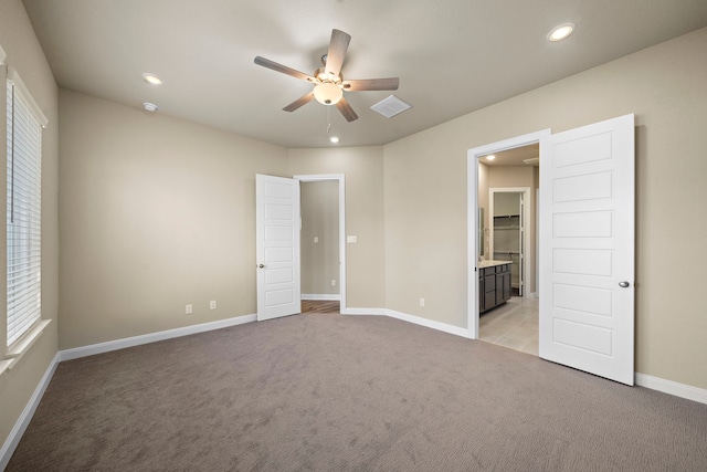 unfurnished bedroom featuring light carpet, connected bathroom, and ceiling fan