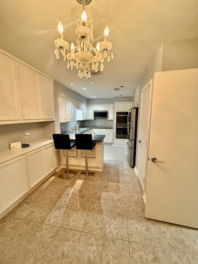 kitchen featuring a chandelier, stainless steel appliances, white cabinets, decorative light fixtures, and tasteful backsplash