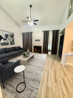 living room featuring ceiling fan, vaulted ceiling, and light hardwood / wood-style flooring