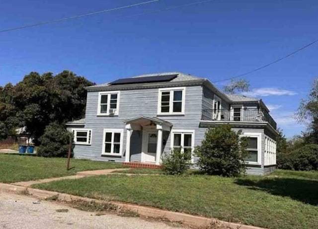 view of front of property with solar panels and a front lawn