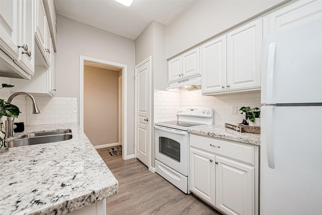 kitchen with light stone counters, white appliances, sink, light hardwood / wood-style flooring, and white cabinetry